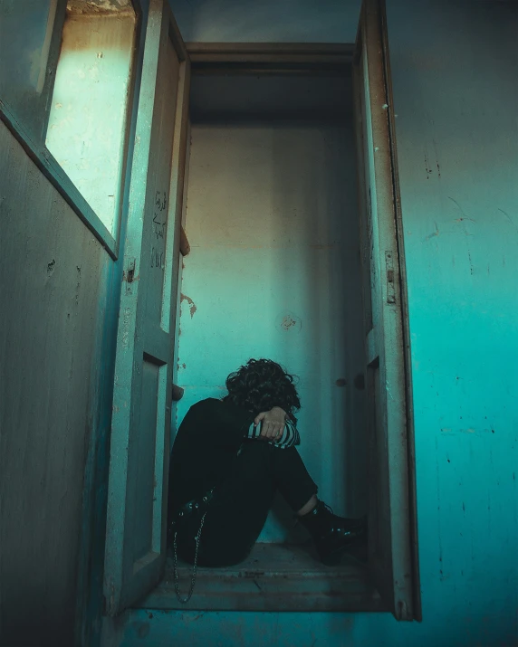 a man sits in a doorway with his hand on the head