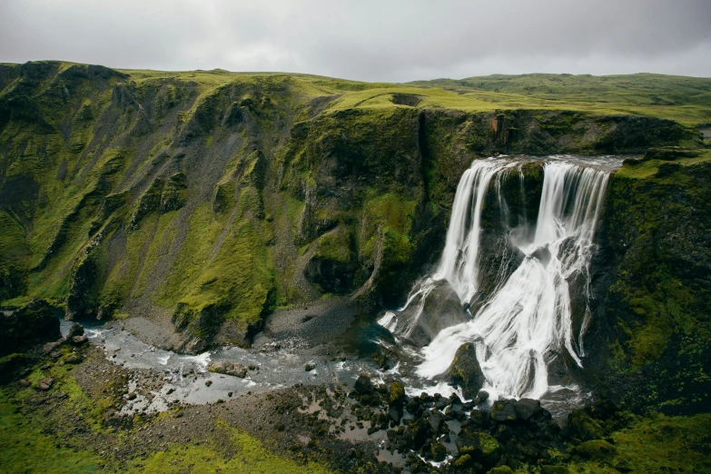 a waterfall running through the middle of a lush green hillside