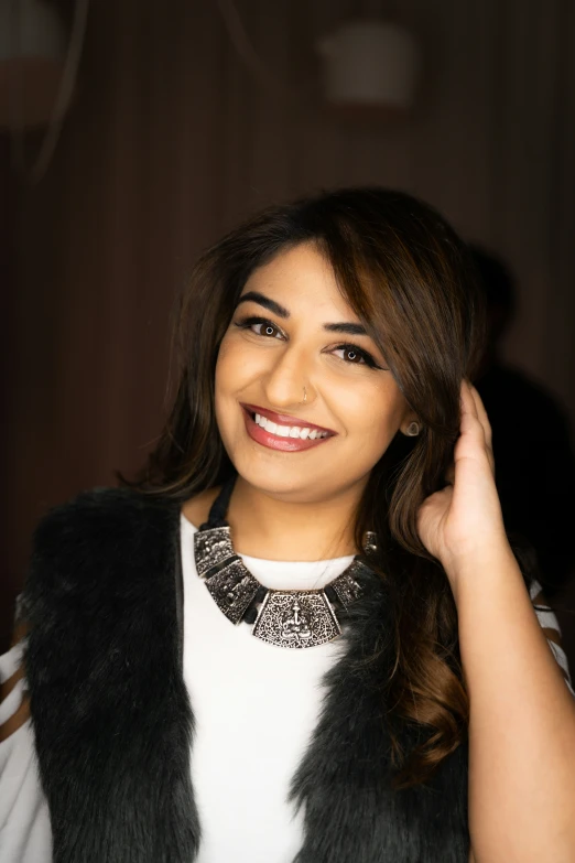 a close up of a woman smiling wearing a fur vest