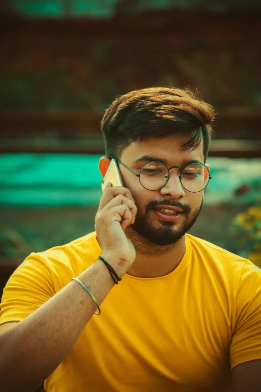 the young man in glasses is talking on his cell phone