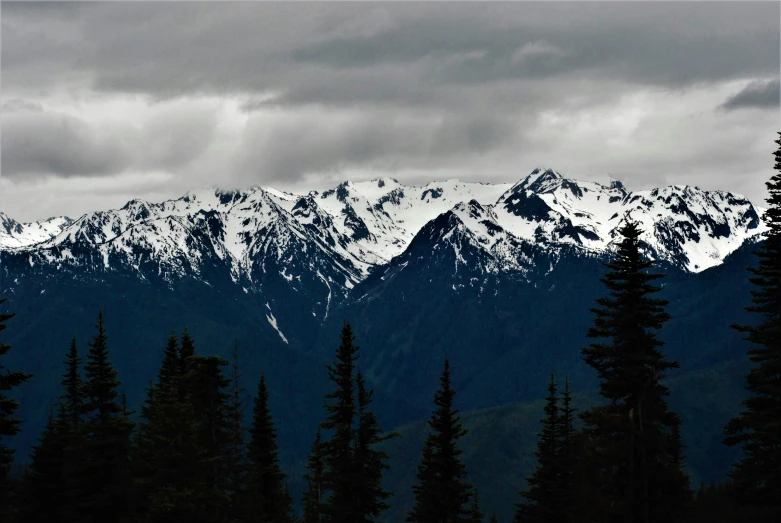 a snow covered mountain range on a cloudy day