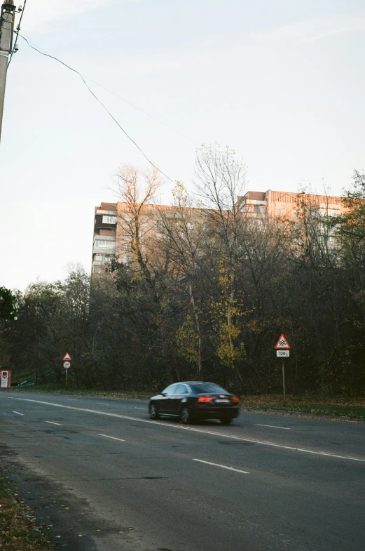 a car drives down the street with a hill in the background