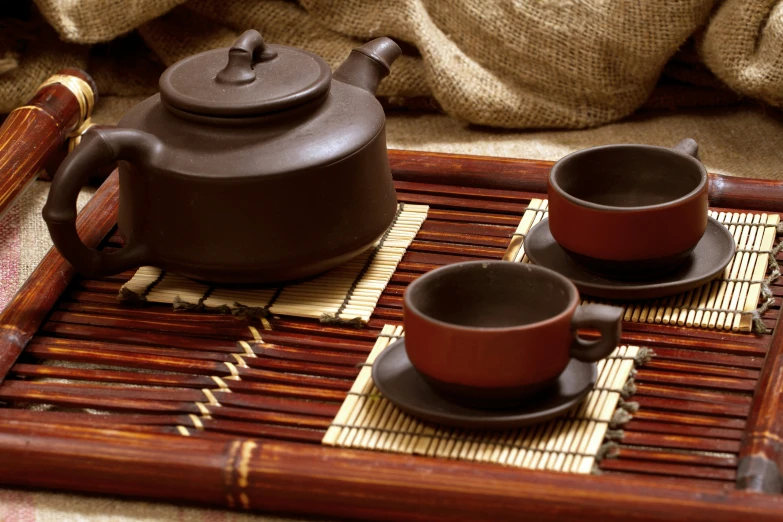 three black cups and saucers on a bamboo tray