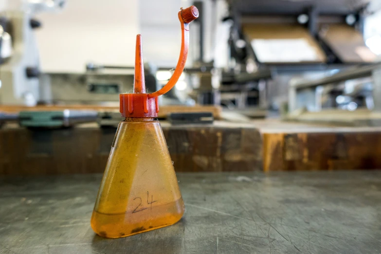 a beaked glass bottle with a red handle is sitting on the table