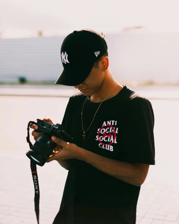 young man holding camera in hands while looking at screen