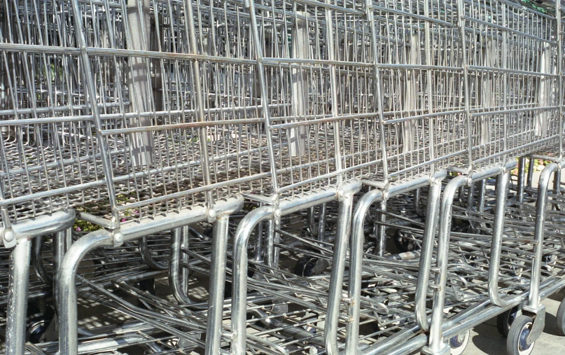 a large row of shopping carts sitting on the side of a street