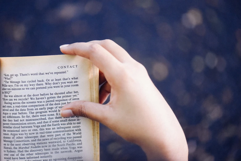 a hand holding up an old book in an image