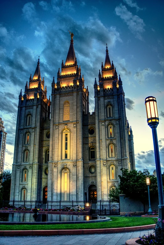 a large cathedral lit up at night with the sky partially cloudy