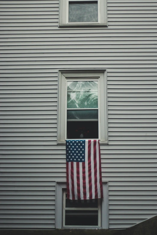 an american flag hangs on a pole outside the window