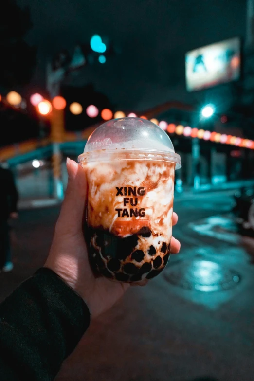 person holds up a cup with some type of drink