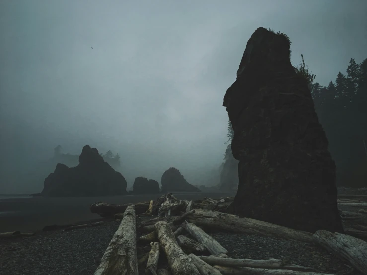 a large rock formation next to the ocean on a gloomy day