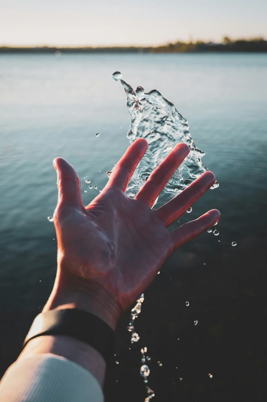 the hand of a person is reaching for a clear water bottle