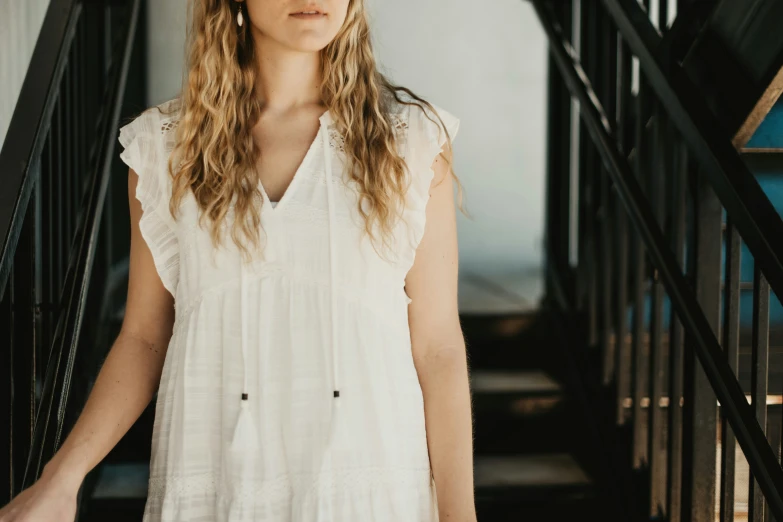 a woman wearing a dress stands on stairs