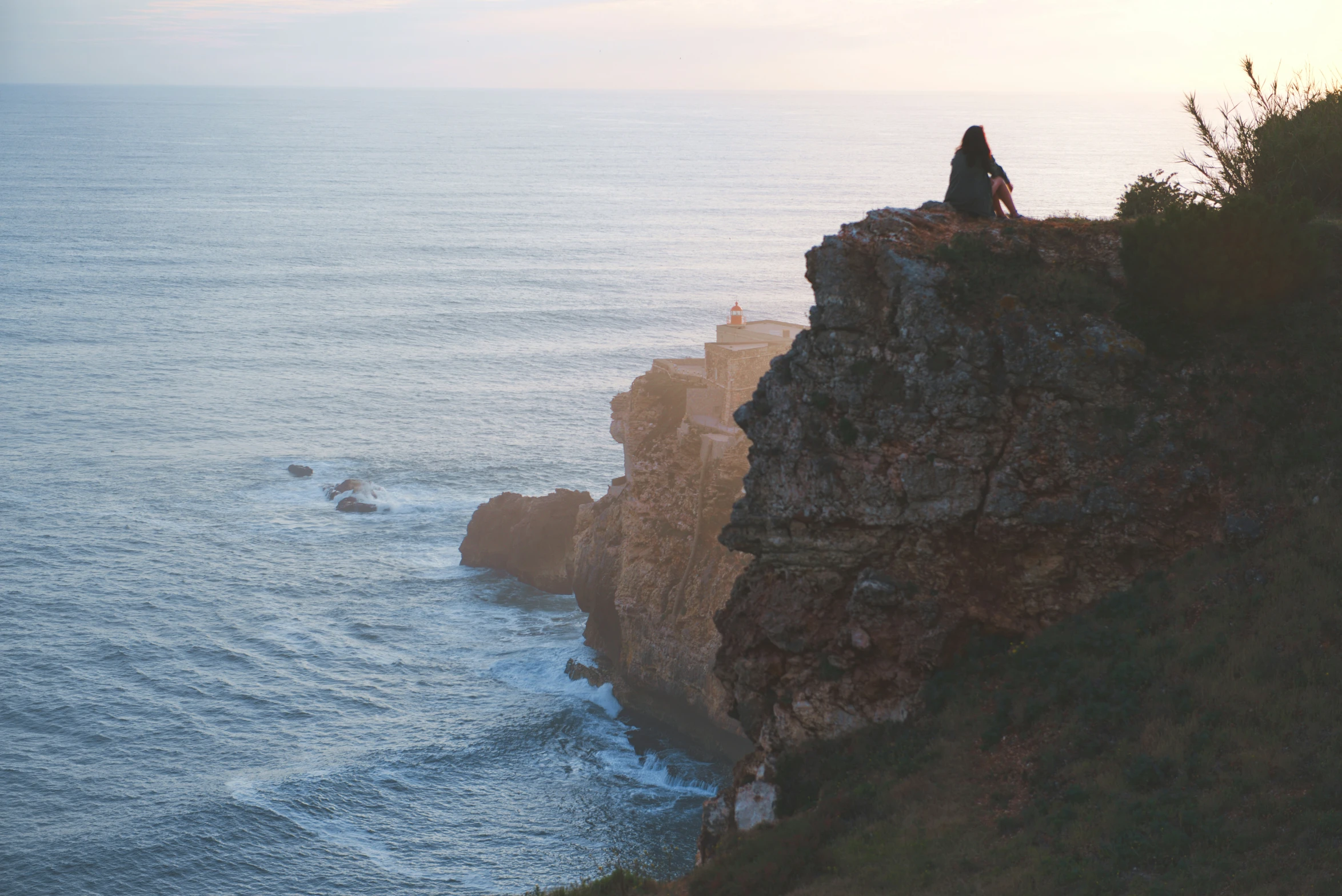 a person on top of a large cliff overlooking the ocean