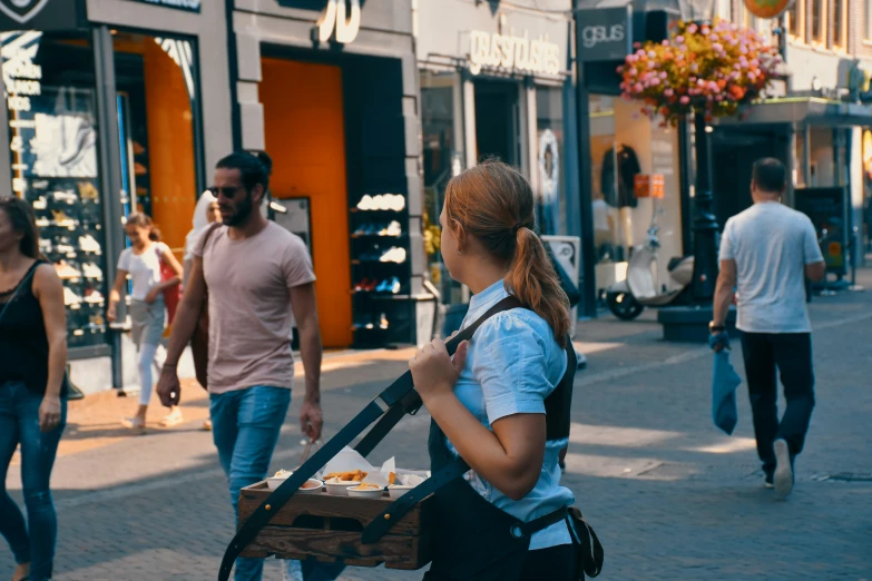 some people walking down the street and two men one of which is carrying a wooden box