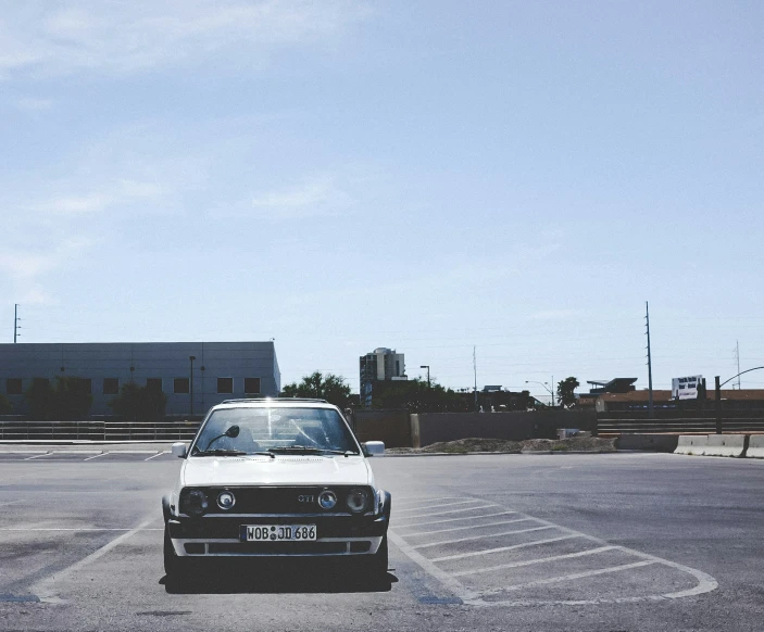 a small white car parked in the middle of a parking lot