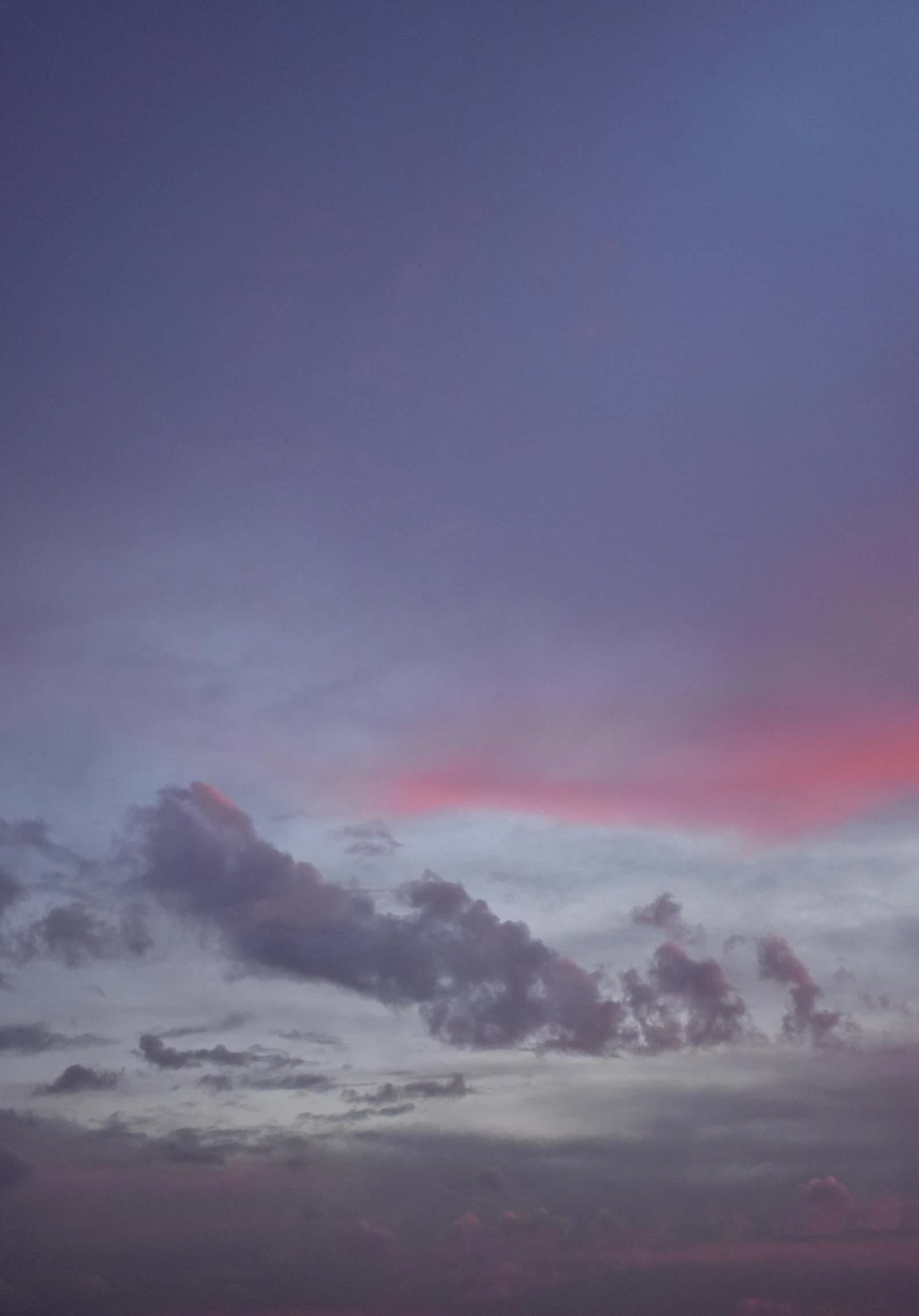 a plane flying into the sunset as clouds loom overhead