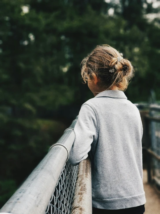 a child standing on a railing looking over a bridge