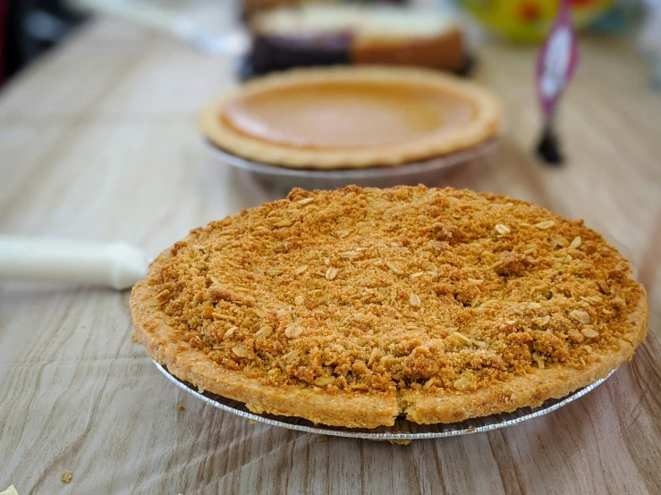 a close up of two pies on a table with other dessert items