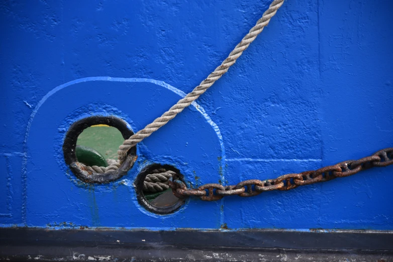 a metal rope and disc stuck to a blue wall