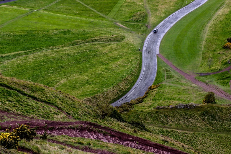 a winding road in the middle of some green rolling hills