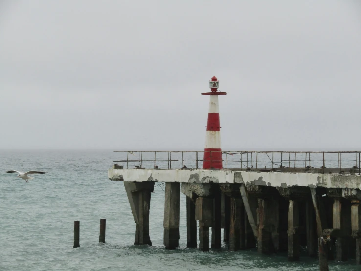 the lighthouse on the beach is next to the pier