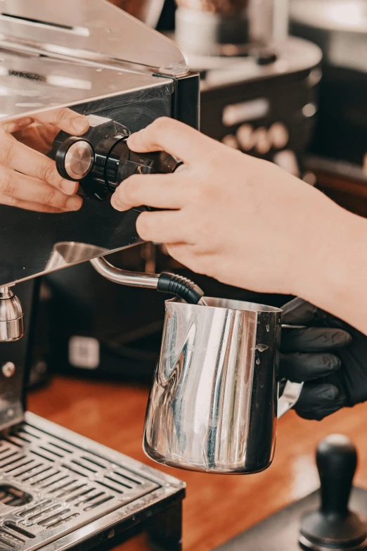 a woman is holding a coffee pot and pressing the on on a machine