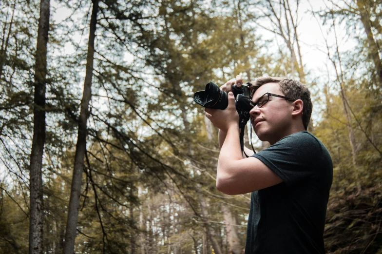 a man in glasses and a t shirt is taking pictures