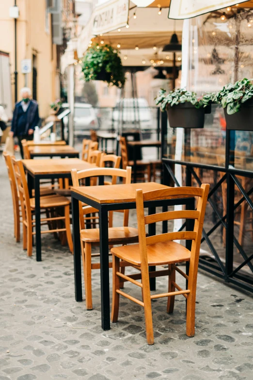 a number of wooden tables and chairs on a street