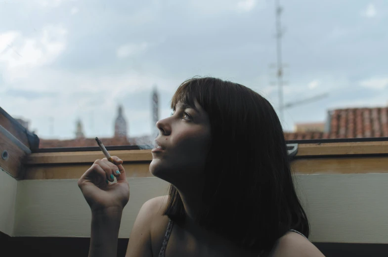 a woman is leaning against a window with her cigarette