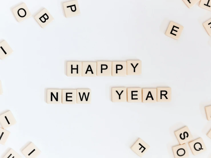 wooden scrabble letters spelling happy new year next to scrabble tiles