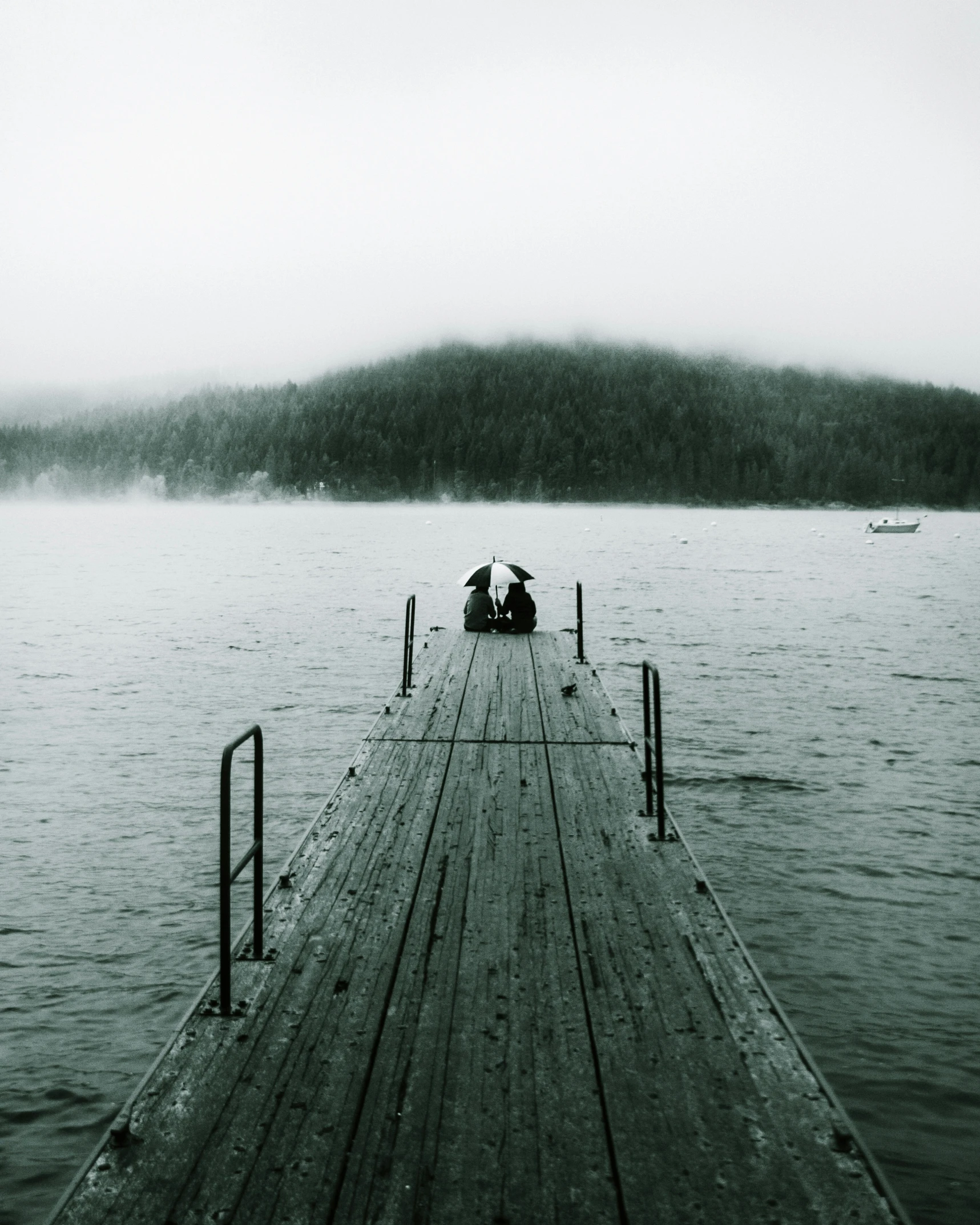 three people on a pier on a lake on a foggy day