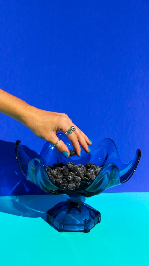 a woman's hand on a glass bowl of rocks