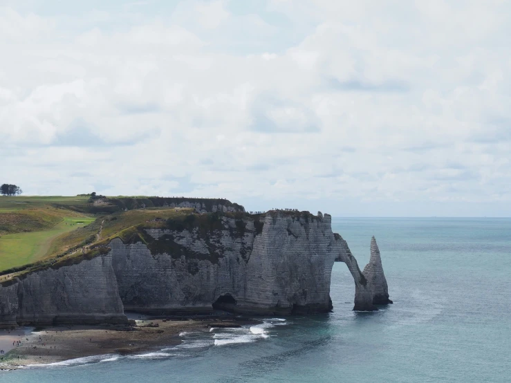 a rock outcropping near a grassy and grassy coast