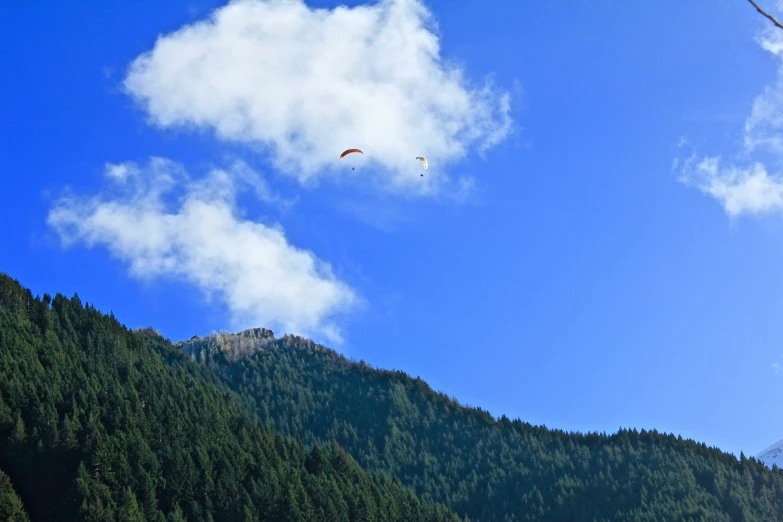 a large bird is flying in the air over mountains