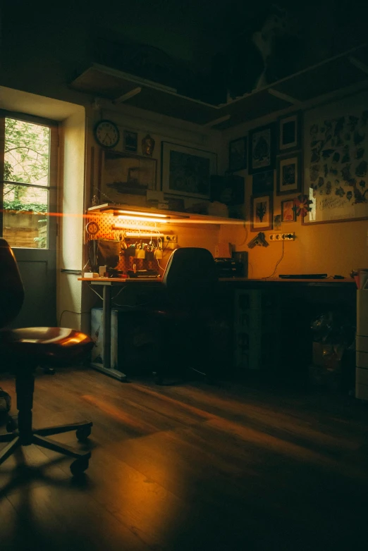 a desk and chair lit by an orange light in a darkened room