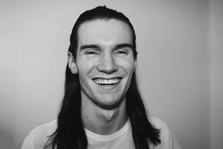 a man with long hair smiling into the camera