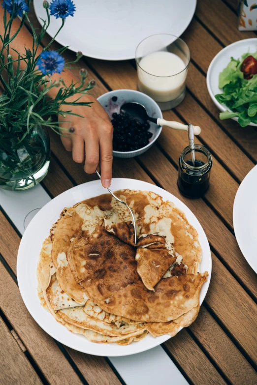 some pancakes on a white plate and some blue flowers