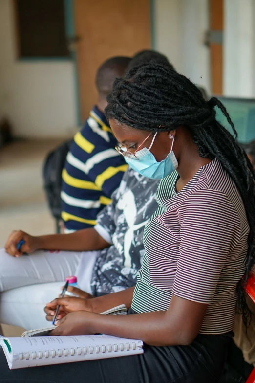 the young woman is wearing a mask while using her notepad