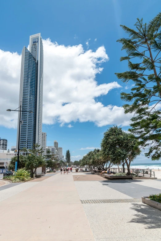 the sidewalk leads from the beach to the water and is surrounded by tall buildings