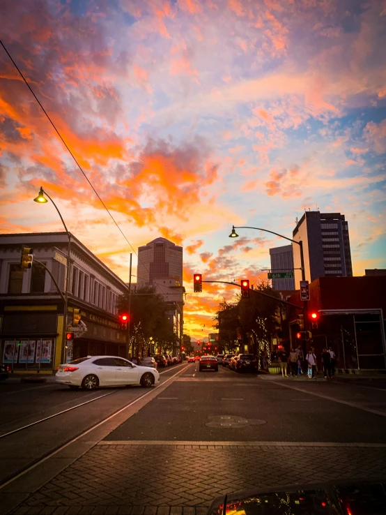 a sunset in the street with several cars waiting