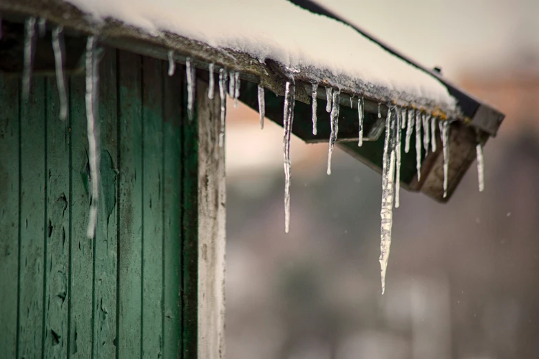 a group of icicles sitting on top of a green wooden fence