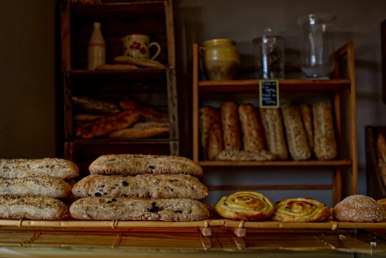 several breads sitting on a wooden table, with plates and coffee mugs