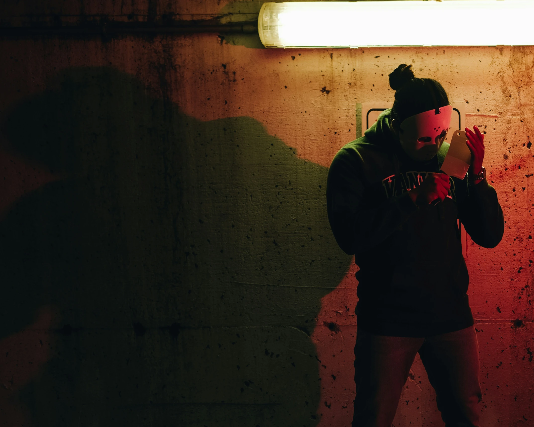 a man wearing a hat standing in front of a red light