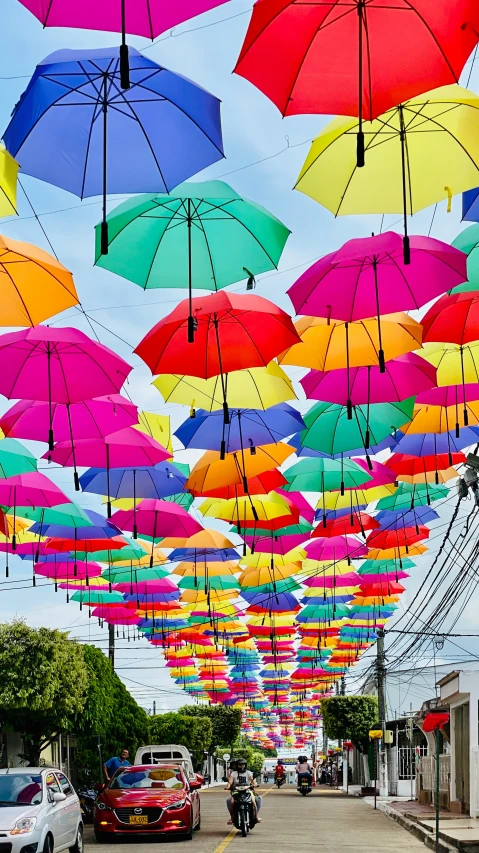 a group of many colorful umbrellas flying above a road