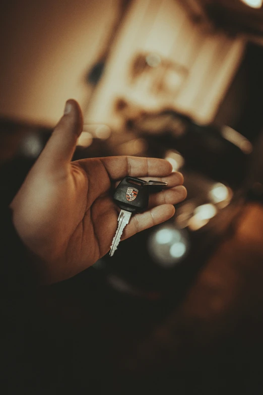 a person is holding a car key and sitting on a car