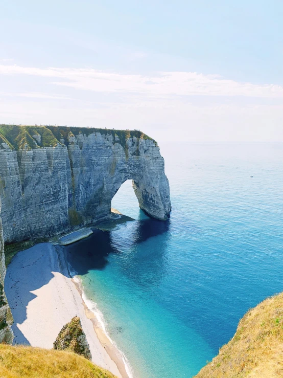 a rocky cliff with water near a sandy beach