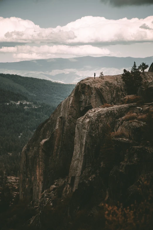 people on the edge of a cliff by a mountain