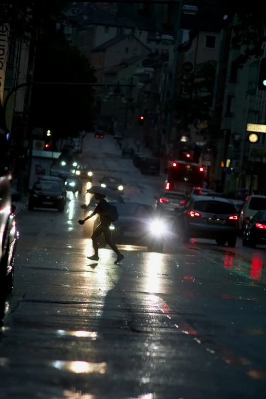 the person is walking down the city street in the rain with an umbrella