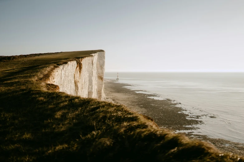 a large cliff near the water with a white wall